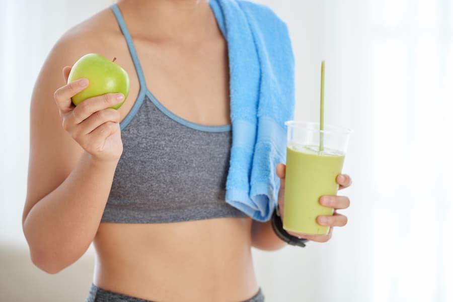 mulher com uma mação numa mão e um suco na outra