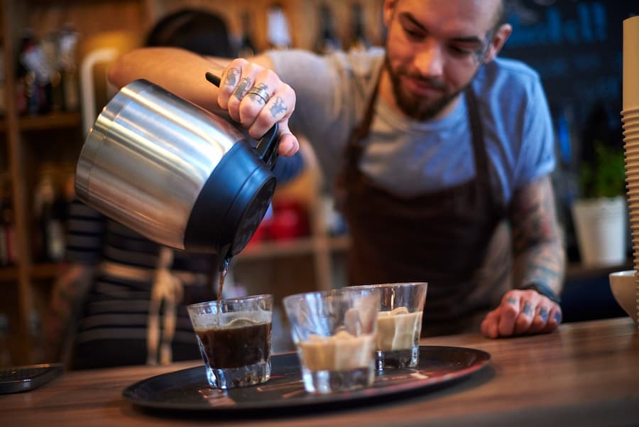 Homem barista serve café em copinhos de vidro
