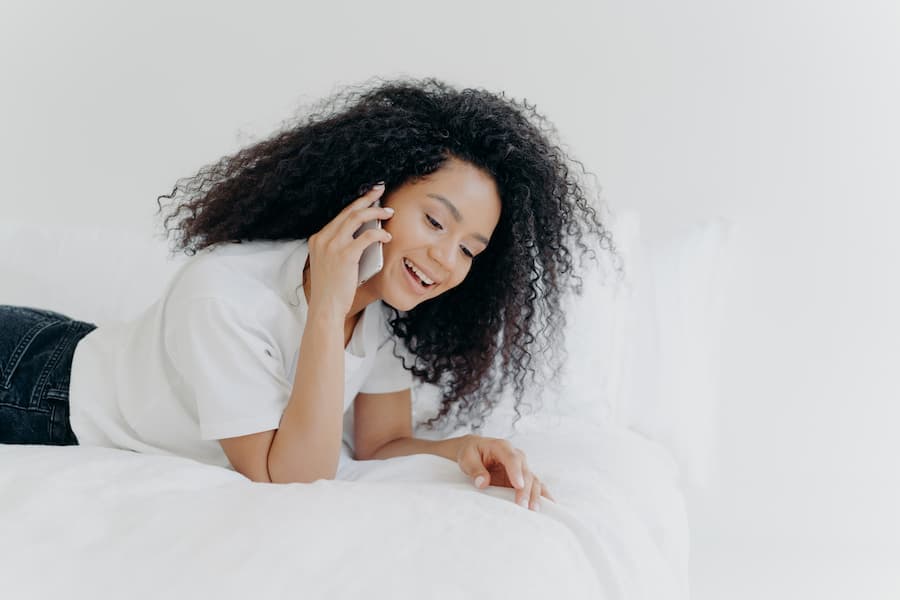 Jovem mulher com cabelos cacheados e longos conversa ao celular