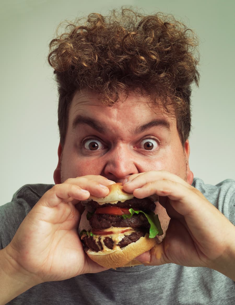 Homem morde um hamburguer com muita fúria