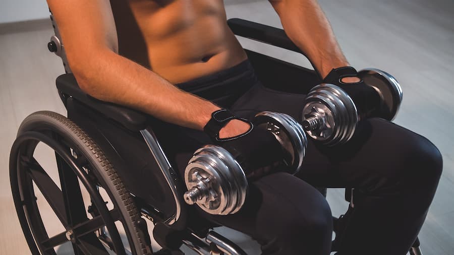 homem cadeirante faz exercícios com um halteres em cada mão