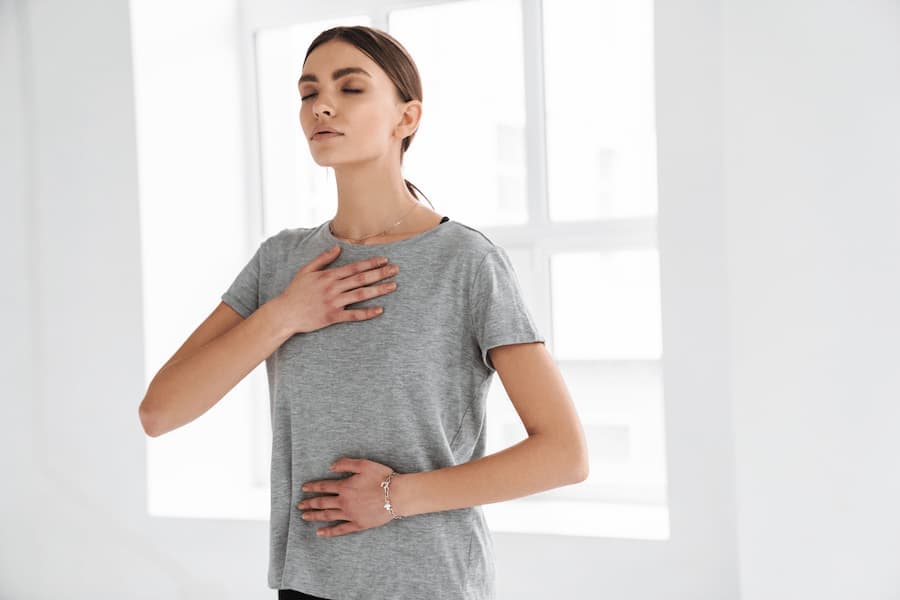 mulher respira com uma mão no peito e outra no abdome