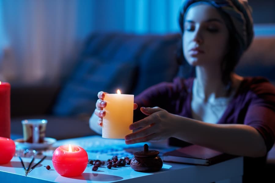 mulher prepara mesa com velas e cristais para fazer ritual místico
