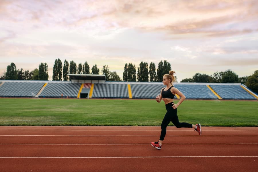 Mulher pratica corrida em pista de atletismo