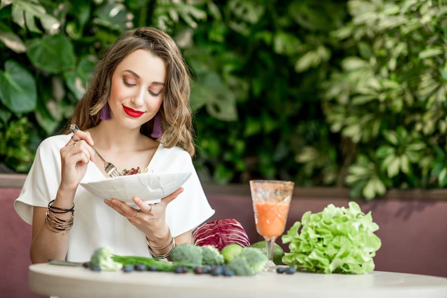 Mulher come salada e toma suco de frutas, na mesa, verduras e legumes