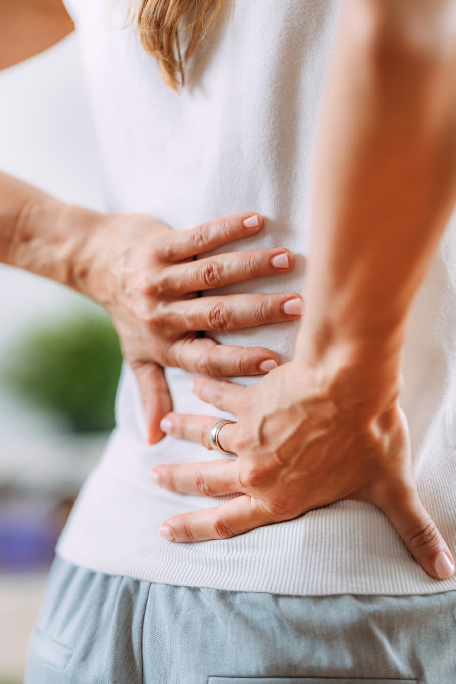 Costas de mulher com as mãos na região lombar