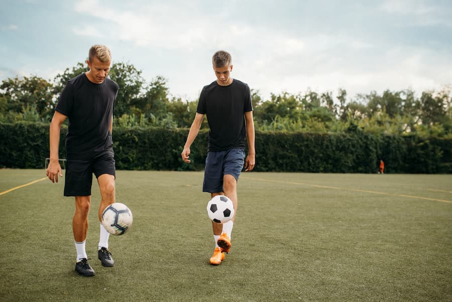 Dois homens jogam futebol num campo