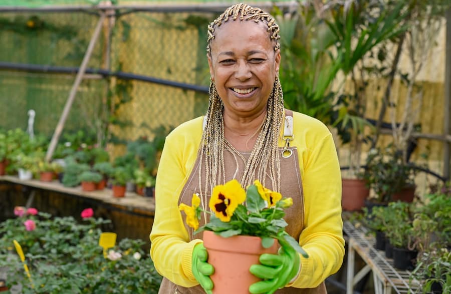 Mulher de meia idade segura vaso de flores em seu jardim