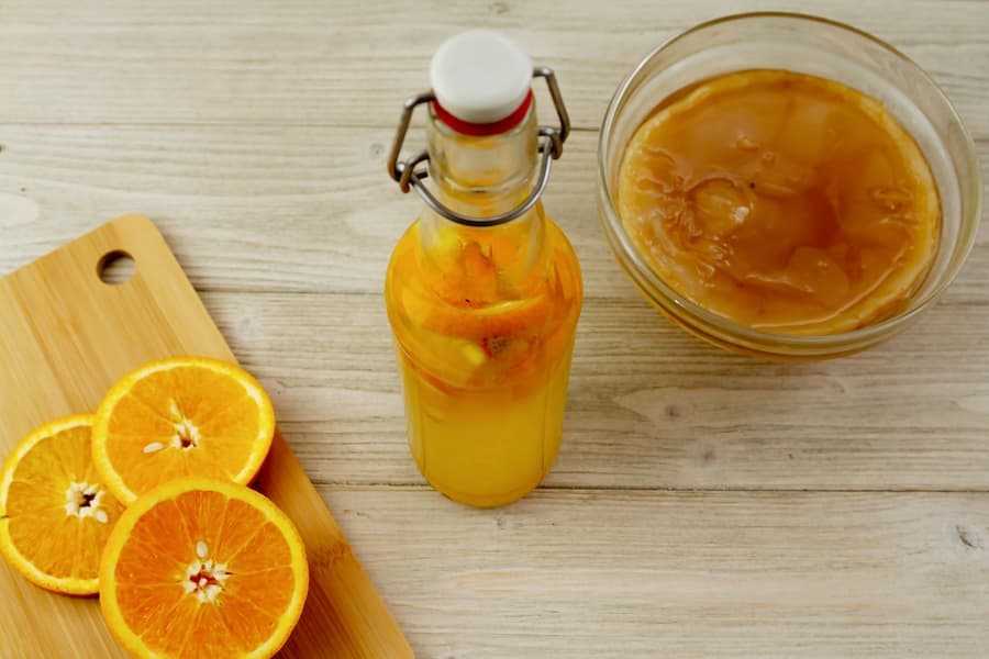 Garrafa e pote de vidro com kombuchá e rodelas de laranja