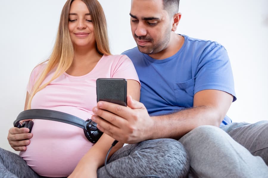 Casal ouve música com fone na barriga da mulher, que está grávida