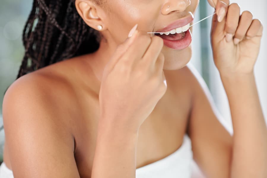 Mulher jovem passa fio dental