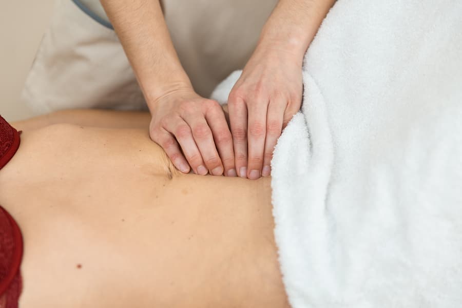Fisioterapeuta faz manobras no abdomem de uma mulher