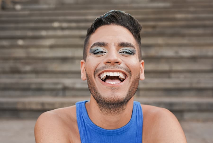 Homem jovem, sorridente e maquiado