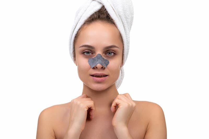 Jovem mulher depois de um banho com uma máscara de pano no rosto para remover cravos