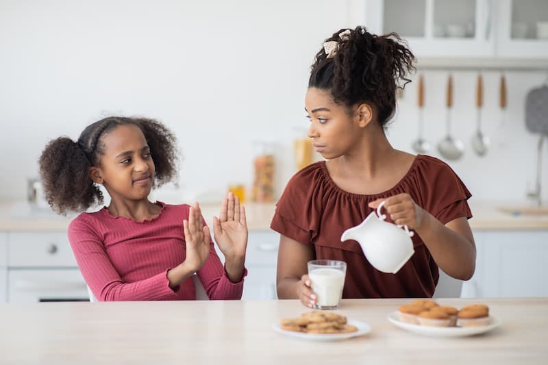 Criança negra recusando leite para a mãe