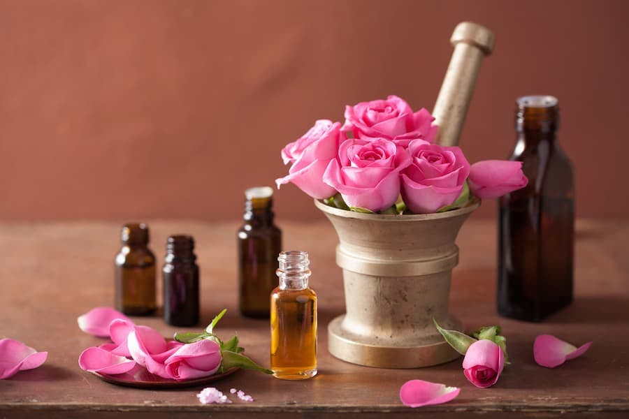 vidrinhos com óleos essenciais e vaso com rosas