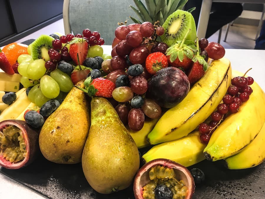 Frutas sobre uma mesa - peras, bananas, uvas, ameixas, maracujá, kiwi.