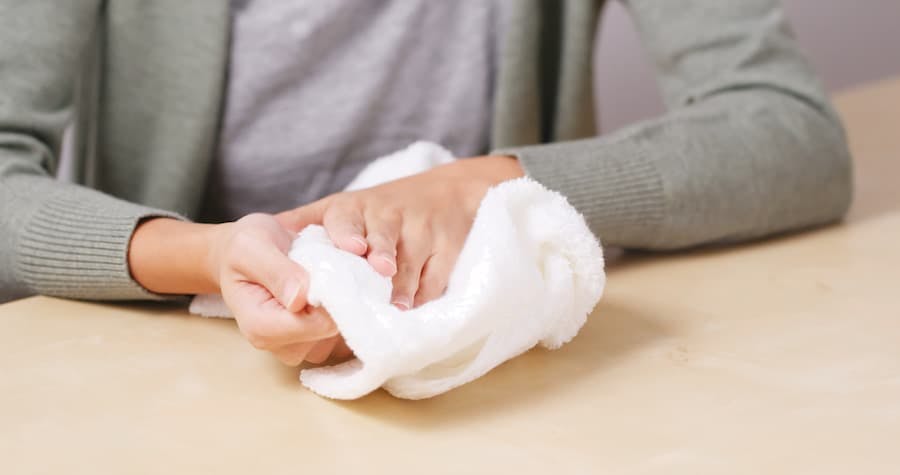 Mãos de mulher com uma toalha enxuga o suor