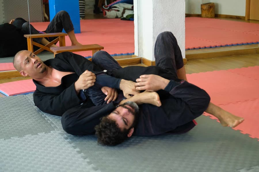Dois homens lutam jiu-jítsu em academia