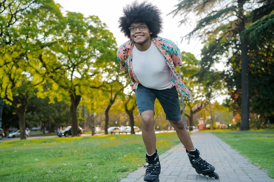 Rapaz de óculos e black power patina ao ar livre