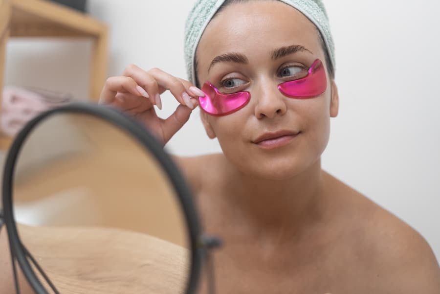 Mulher em frente ao espelho usa máscara de tratamento nas olheiras