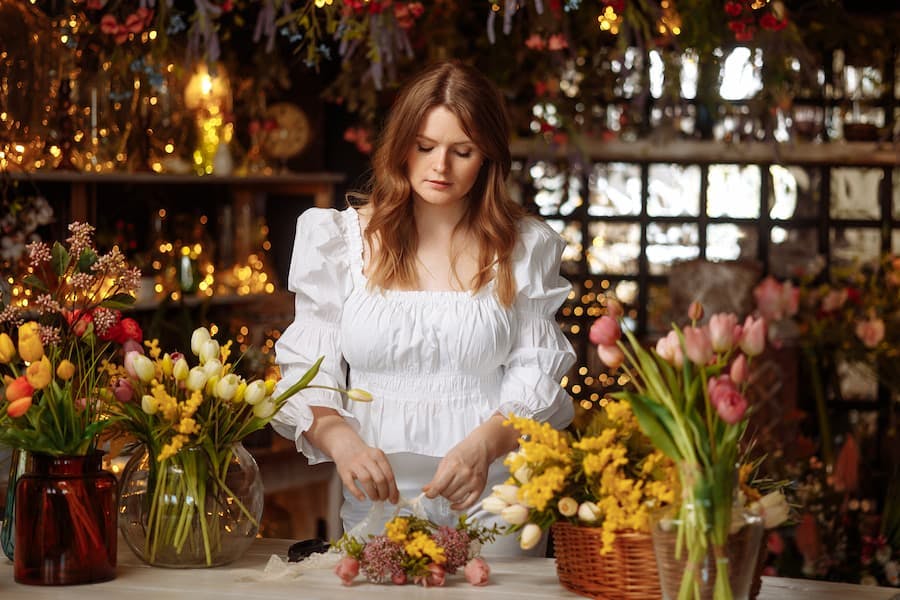 Mulher jovem trabalha com arranjos florais