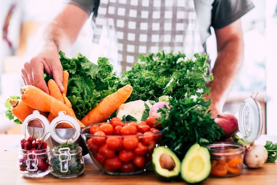 Homem prepara alimentos vegetarianos, legumes e verduras