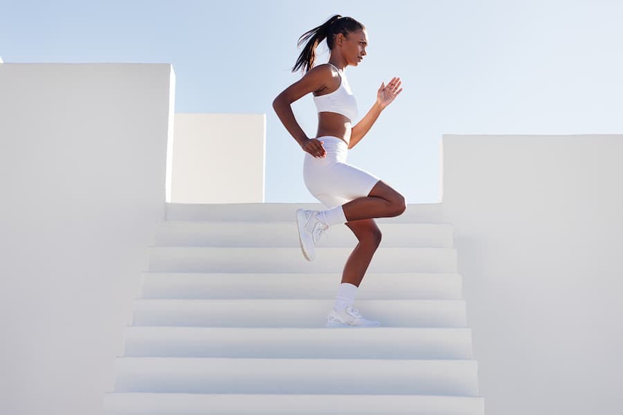 Mulher jovem faz exercícios em escadaria ao ar livre