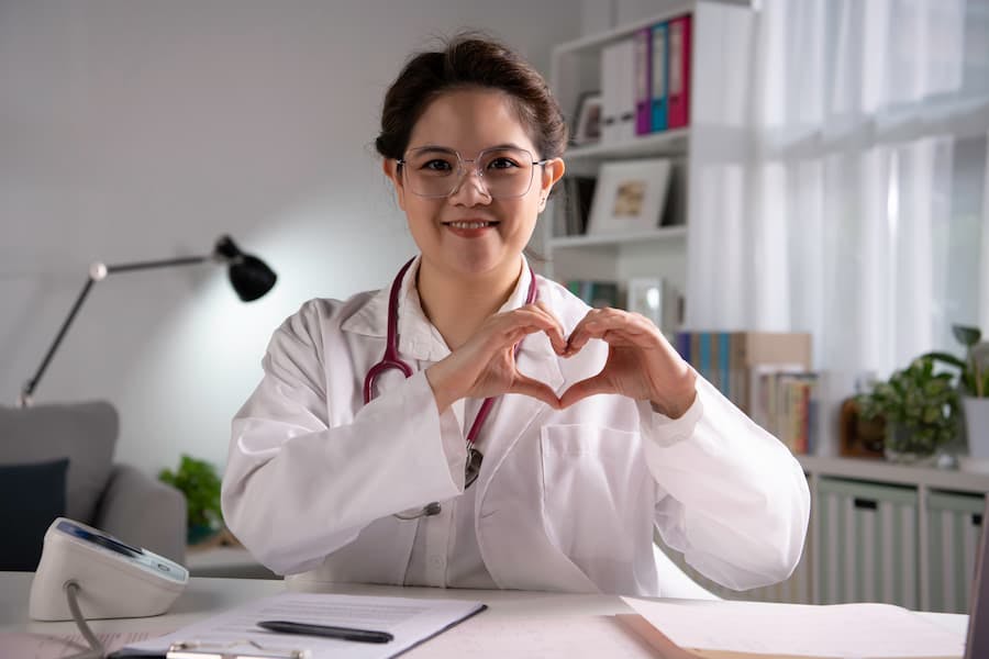 Médica faz sinal de coração com as mãos