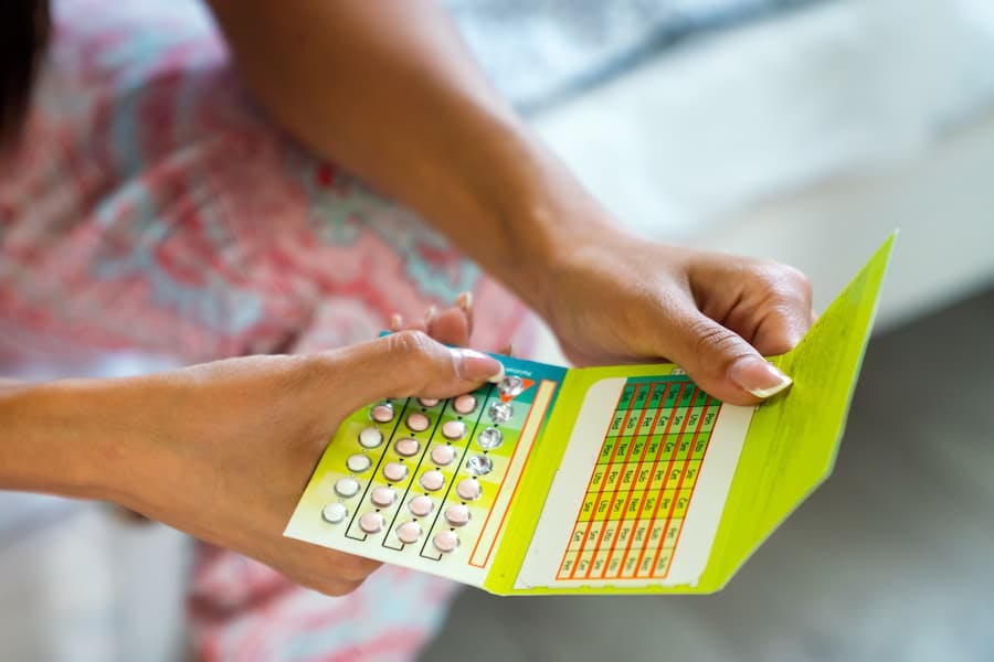 Mãos de mulher seguram cartela de pílulas anticoncepcionais